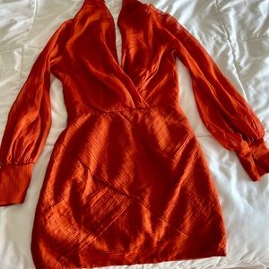 Orange mini dress with long, sheer sleeves, and plunge neckline